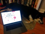 Laptop displaying audiobook cover art for Lock In next to a sleeping dog.